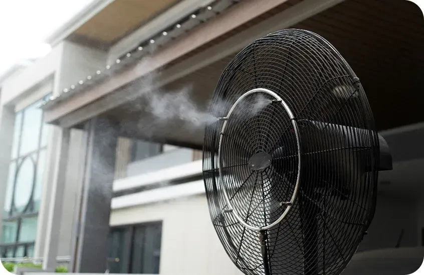 Wall-mounted misting fan spraying fine mist on a residential patio - choosing the best misting fans for outdoor use